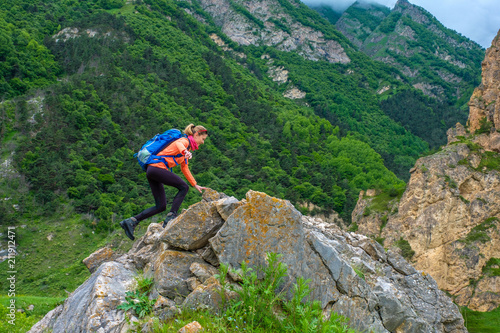 Girl with a backpack in the mountains.