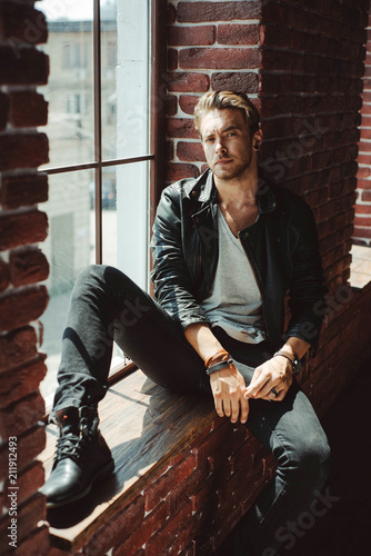 Stylish handsome caucasian man on a brick wall background