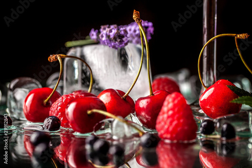 berry cold cocktail with alcohol in a glass crystal glass on a black background with berries, raspberries, strawberries, cherries, with ice. background image. Copy space, selective focus photo