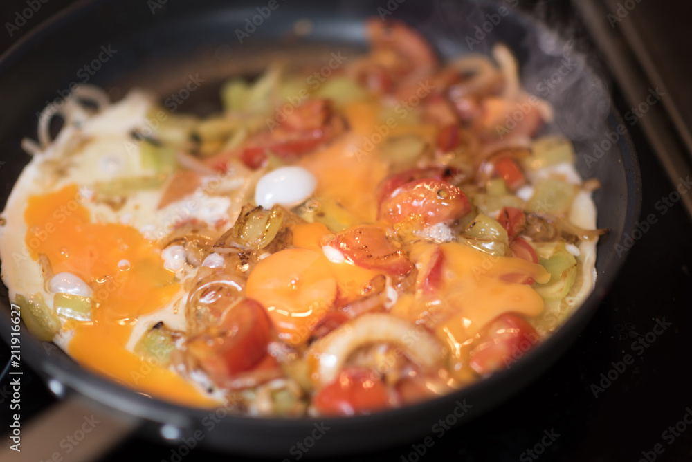 Eggs with tomatoes, green peppers and onions in a frying pan