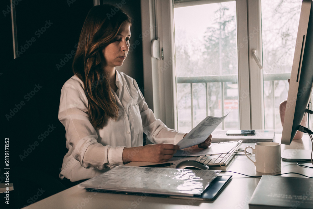 Young businesswoman reading documents at office desk. Young businesswoman reading documents at office desk.
