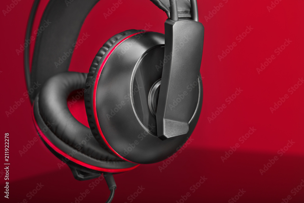 A pair of gaming headphone against a red background with dramatic lighting
