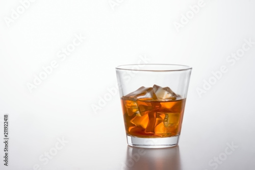 Glass of brandy and ice cubes on white background