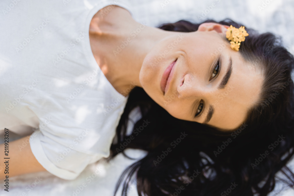Closeup outdoor portrait of beautiful female model relaxing during leisure time in the park, lying on white blanket. Attractive smiling Caucasian woman with pleased expression posing outside. People Closeup outdoor portrait of beautiful female model relaxing during leisure time in the park, lying on white blanket. Attractive smiling Caucasian woman with pleased expression posing outside. People