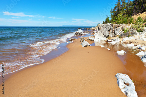 Beautiful sandy beach on the eastern shore of Lake Baikal with white stones and coastal forest on a summer sunny day photo