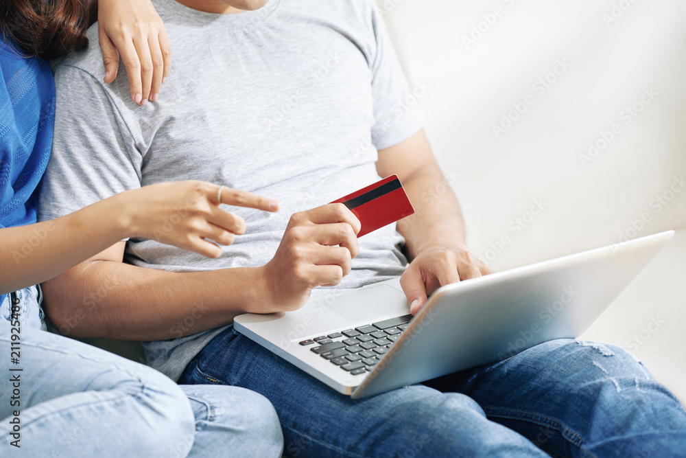 Naklejka premium Faceless shot of couple buying via Internet while using laptop and credit card for shopping