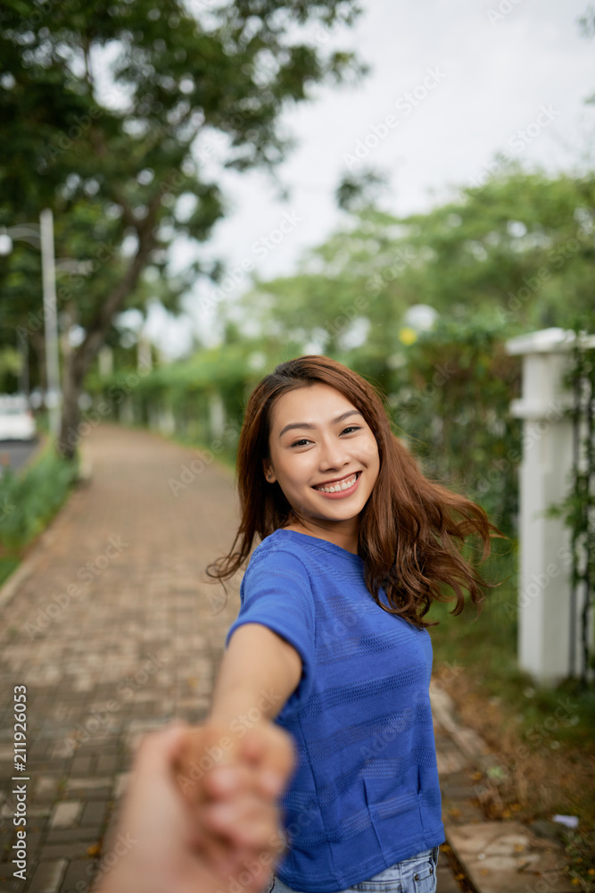 Beautiful Asian woman holding hand of crop anonymous beloved man asking to follow her while strolling in park Beautiful Asian woman holding hand of crop anonymous beloved man asking to follow her while strolling in park