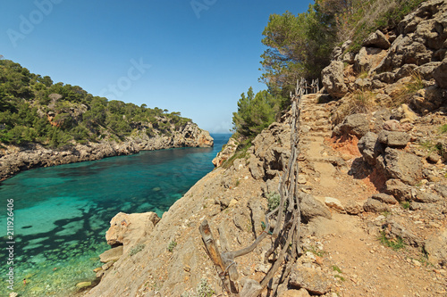 Hiking trail next to a beautiful cove with turquoise and transparent waters in Cala Deia Majorca. Adventure vacation concept.