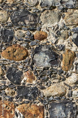 Old English stone town wall surface embedded with ancient flint.