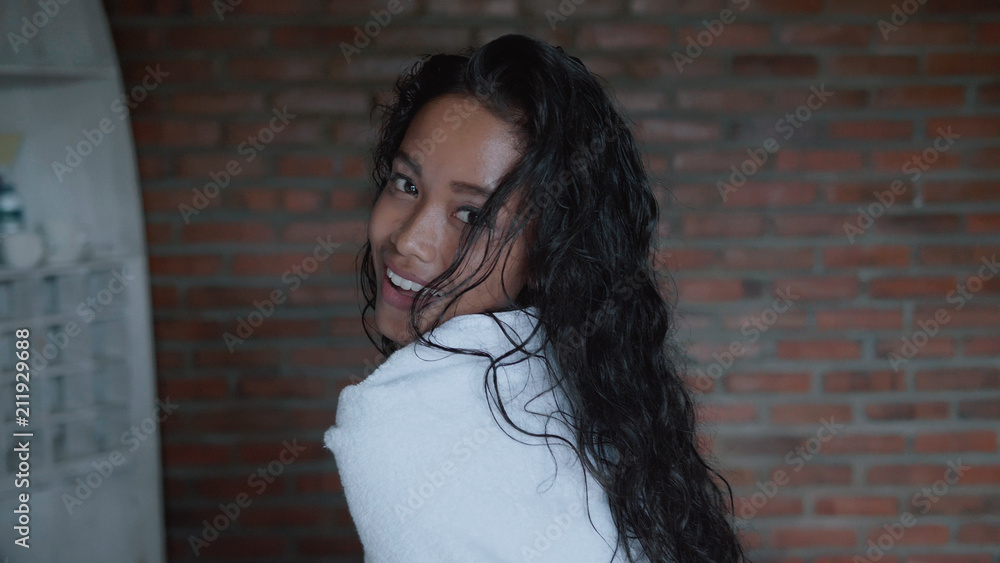 Fototapeta premium Beautiful lady after shower covered in white towel relaxing on bed in her apartment. Portrait of fashion model girl indoors