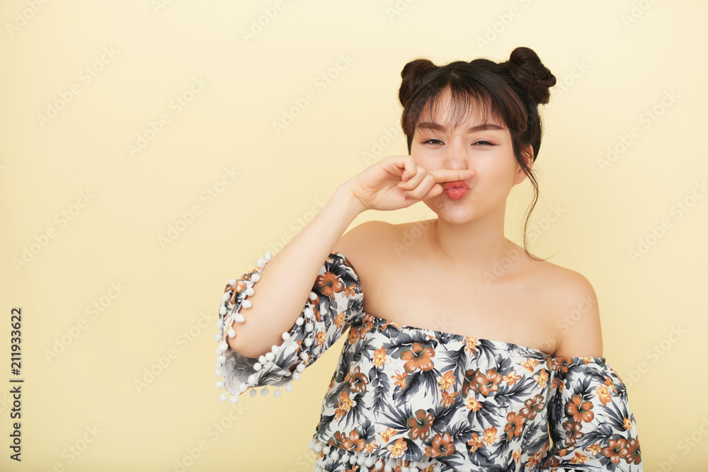 Asian young woman grimacing at camera isolated on beige background Asian young woman grimacing at camera isolated on beige background