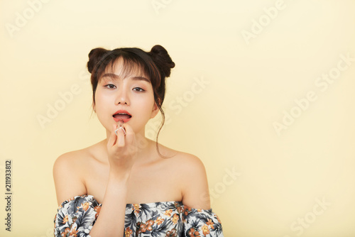 Young Asian girl wearing lipstick on beige background