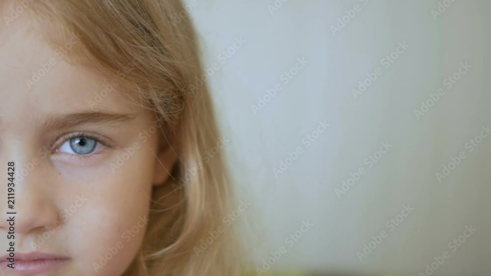 Portrait little young girl with blue eyes looking at camera. Young serious kid looking at camera. Closeup Portrait little young girl with blue eyes looking at camera. Young serious kid looking at camera. Closeup