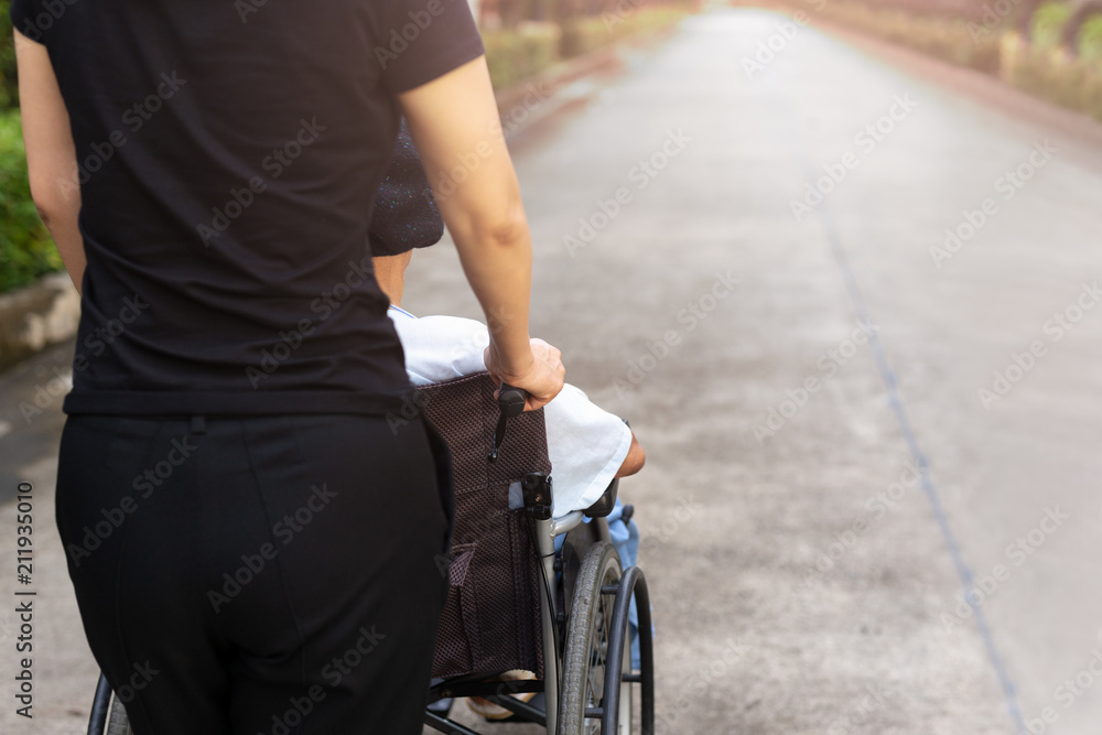 Caretaker spending time outdoor with patient in wheelchair