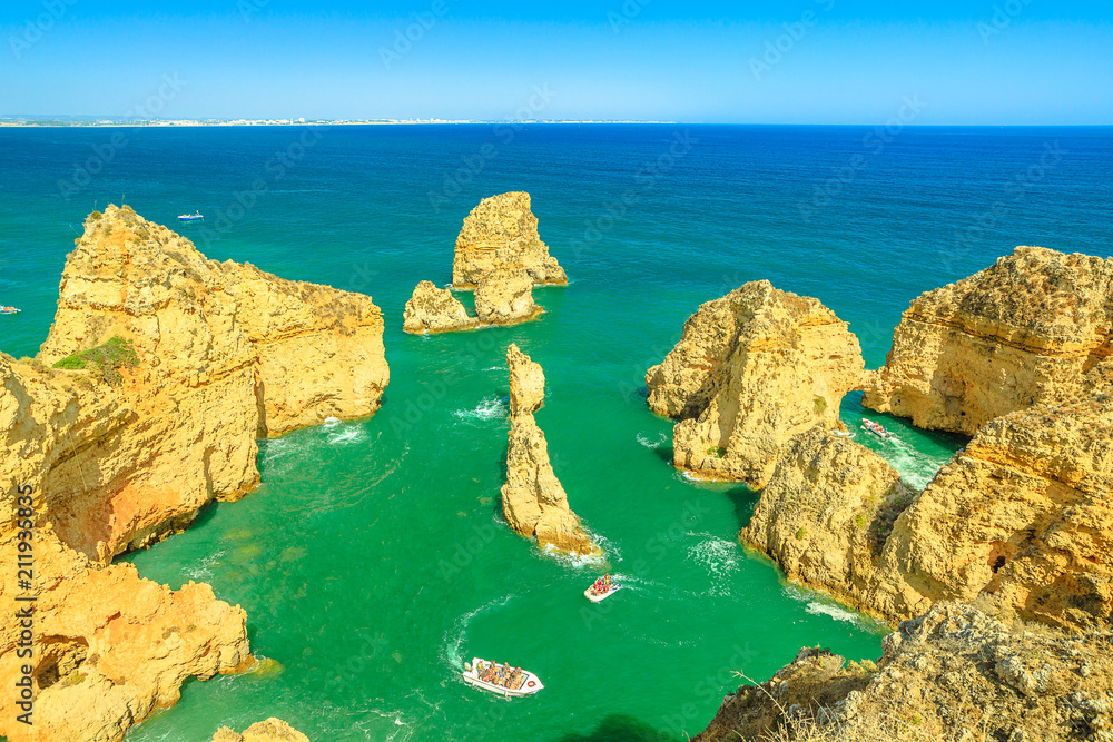Aerial view of landscape in a sunny day of sandstone formations of Ponta da Piedadeof and boat trip between cliffs in Lagos, Algarve Coast, Portugal. Summer holidays. Tour tourism in Atlantic Ocean.