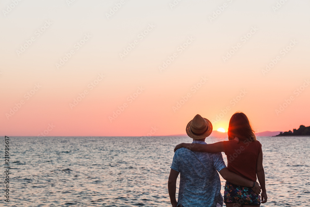 Fototapeta premium Young couple enjoying sunset by the sea