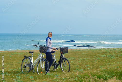 A girl with bicycles looks at the Ocean