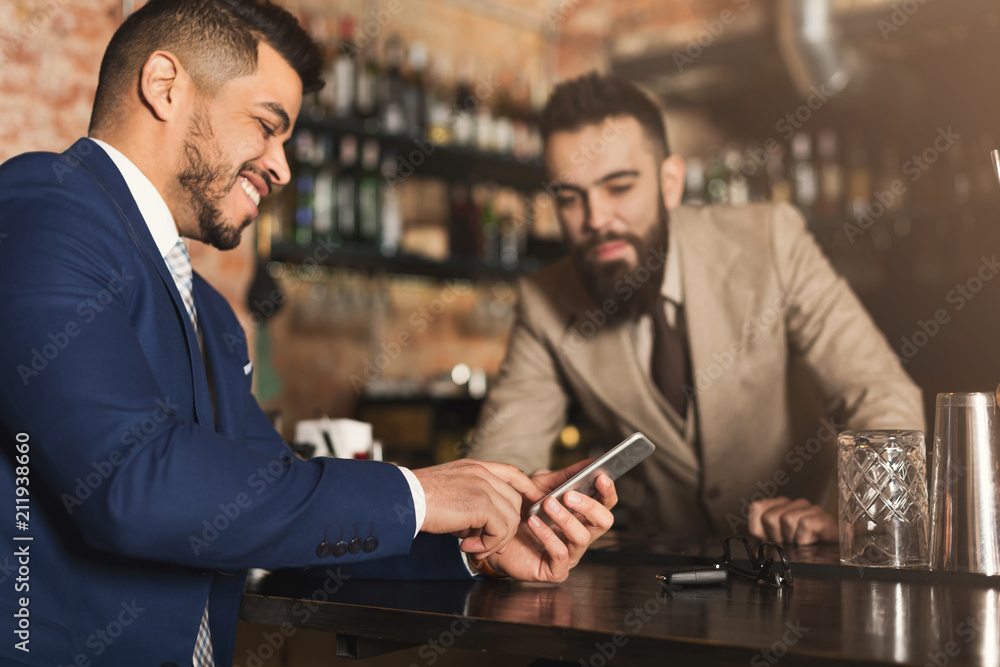 Businessman showing information on phone to barman