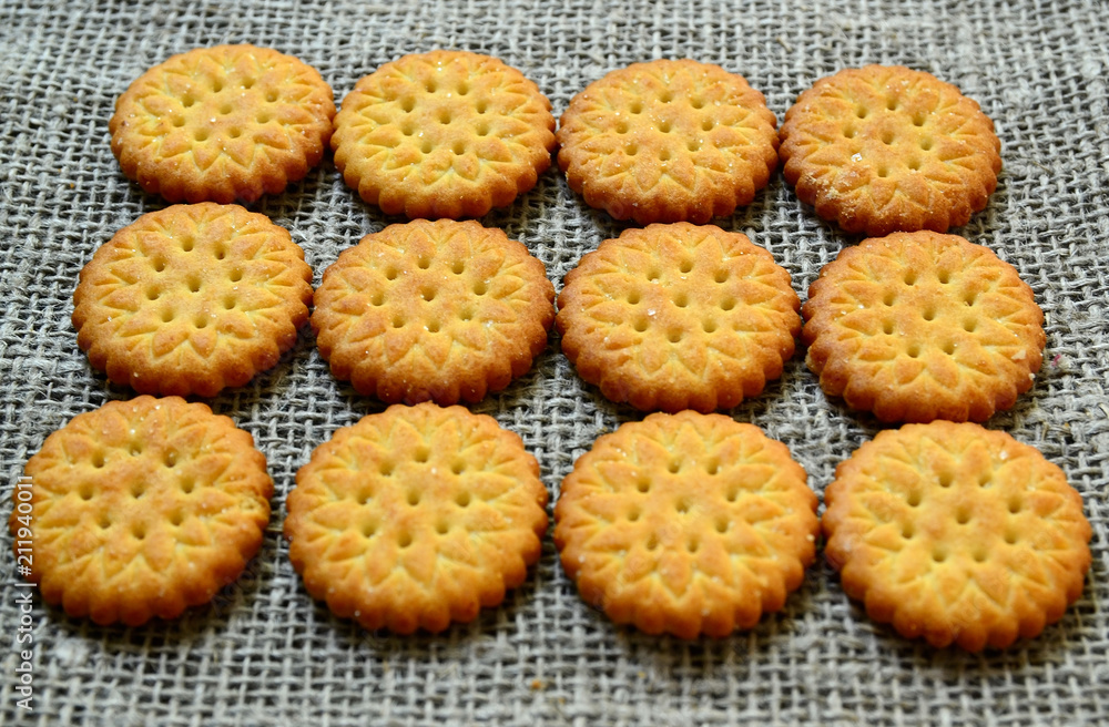 Round delicious salty crackers cookies on a burlap cloth as a background.Crispy baking.Classic snack concept.Selective focus. Round delicious salty crackers cookies on a burlap cloth as a background.Crispy baking.Classic snack concept.Selective focus.