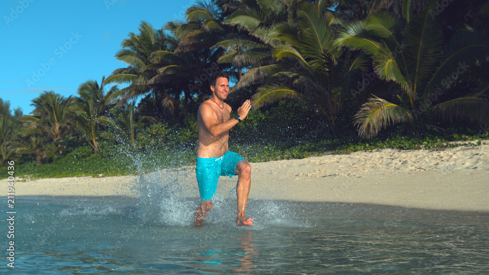 Joyful shirtless man running along the calm ocean and past lush palm trees. Joyful shirtless man running along the calm ocean and past lush palm trees.