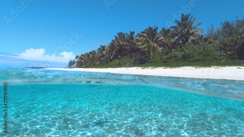 Fototapeta Naklejka Na Ścianę i Meble -  HALF UNDERWATER: Turquoise ocean water washes the breathtaking white sand beach.