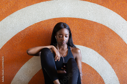 Young woman listening to music against patterned background photo