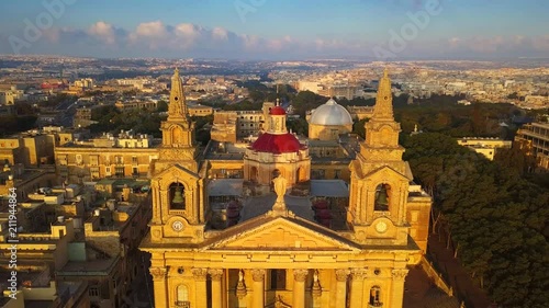 Floriana, Malta - 4K flying away from St. Publius Parish Church at warm sunrise photo