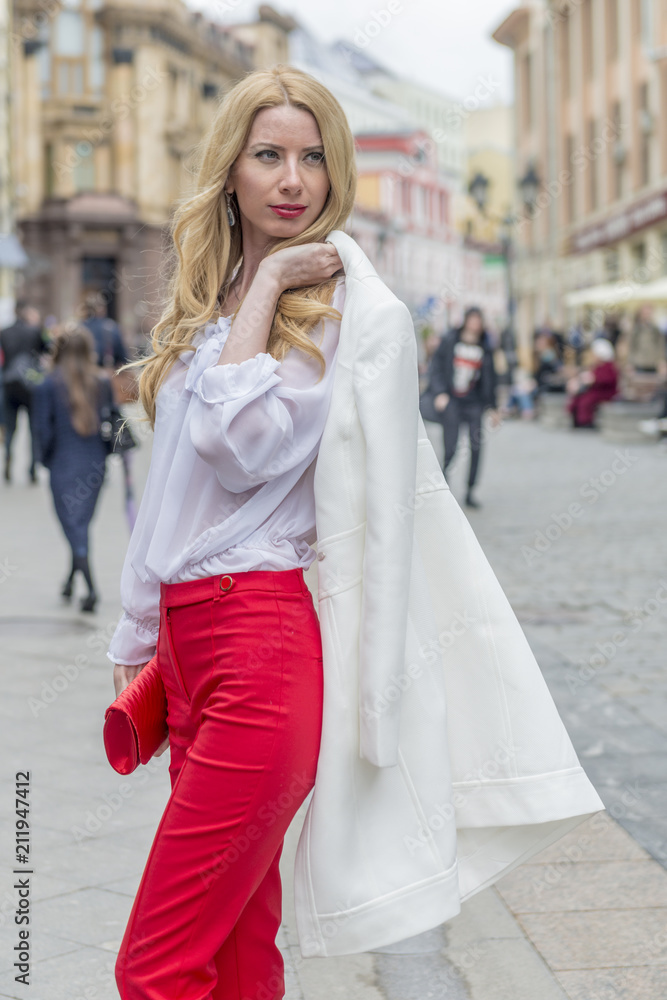 Obraz premium Fashionable young blonde in a spring fashionable suit and with a shopping bag in the center of Moscow