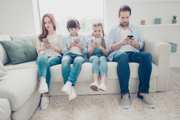 Portrait of family with two kids having holding smart phone electronic device in hands texting sms using wi-fi 5G internet checking email searching contact. Apps concept