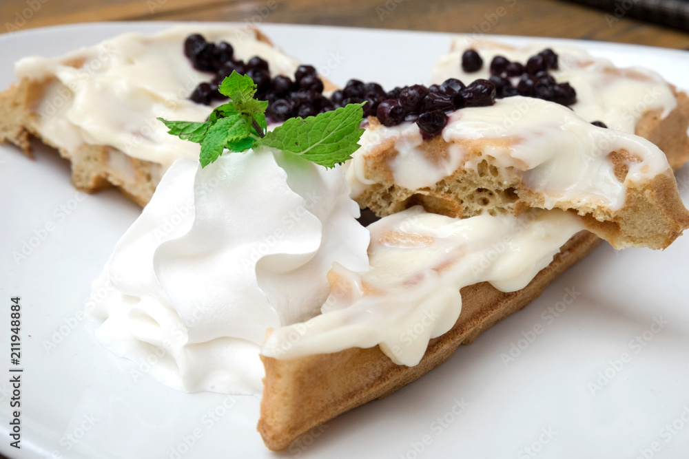Delicious traditional Belgian homemade waffles with sweet vanilla sauce, fresh blueberries and whipped cream served at the confectionery of Novi Sad, Serbia Delicious traditional Belgian homemade waffles with sweet vanilla sauce, fresh blueberries and whipped cream served at the confectionery of Novi Sad, Serbia