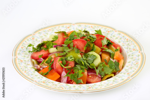 Fresh, healthy and delicious summer vegetable salad with tomatoes, cucumber, green and orange pepper, red onion and parsley