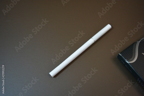 White thin cigarette with ХS filter and packaging on a matte brown background