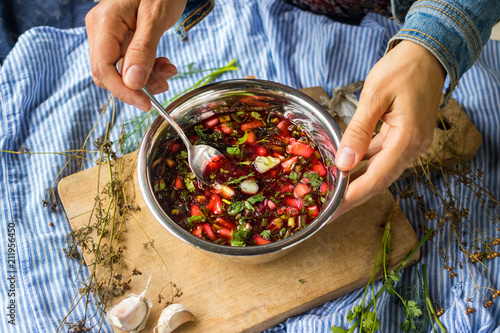 Woman hand holds cold soup Chrianteli with sour cherry or blackberry juice. Georgian traditional summer food with garlic, green herbs, cucumbers. Raw vegan vegetarian healthy food. photo