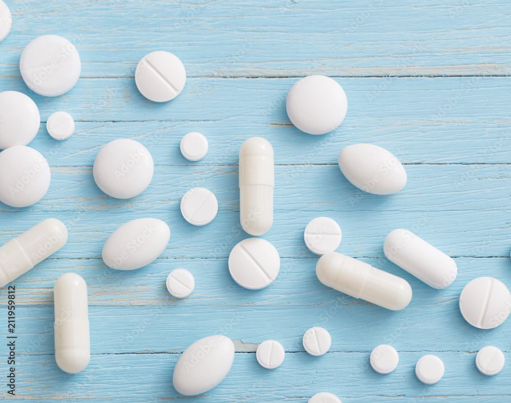 white pills on blue wooden background white pills on blue wooden background