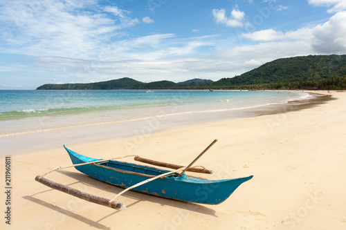 Traditional fishing boat on shore of the ocean with white sand