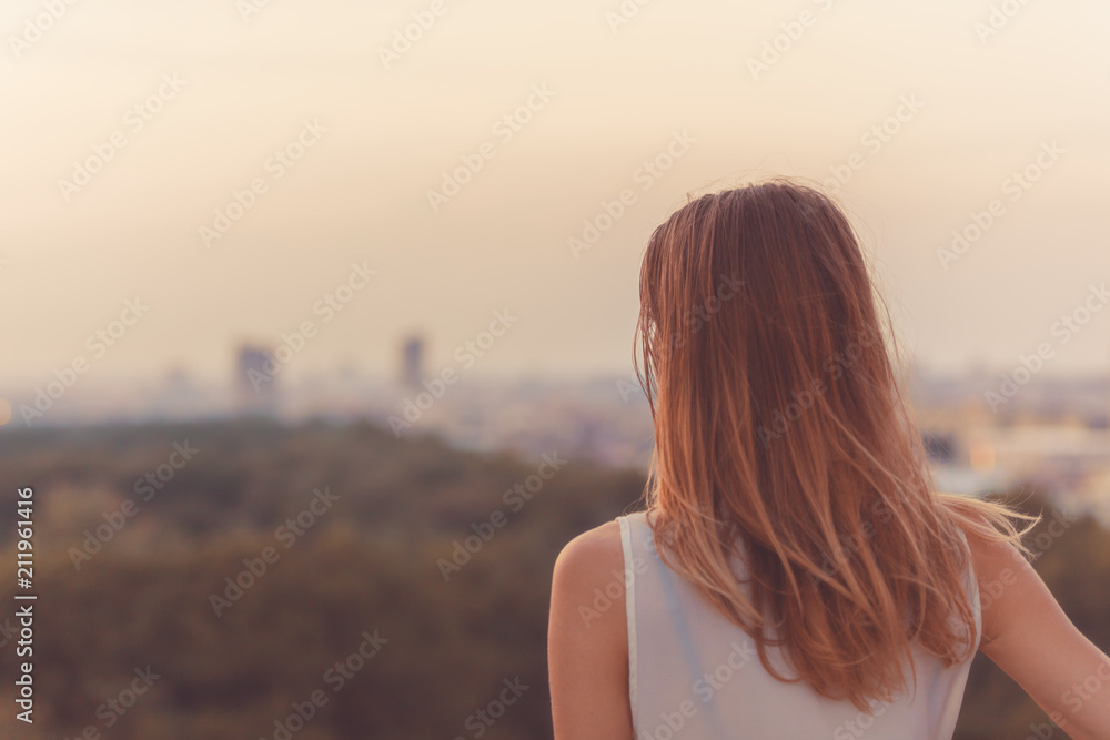 Single woman looking at the distant city landscape. - obrazy, fototapety, plakaty 