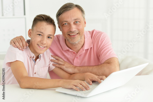 son and father using laptop