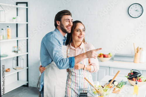 boyfriend pointing on something to girlfriend during cooking in kitchen