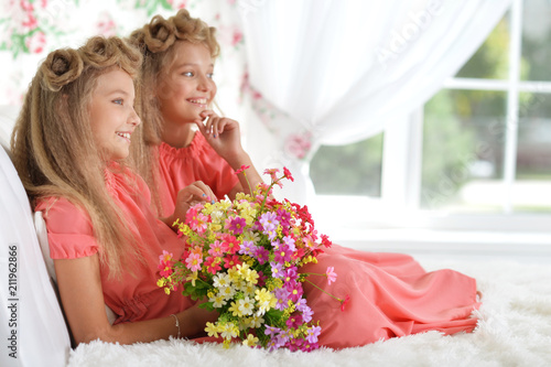 two adorable twin sisters in beautiful pink dresses with bouquet