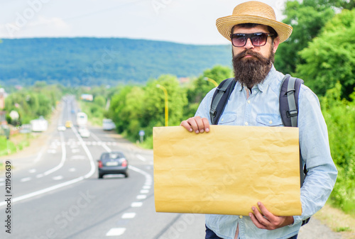 Fotografija Man bearded hitchhiker stand at edge of road with blank paper sign, copy space