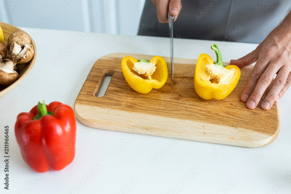 cropped shot of man cutting bell pepper on wooden cutting board cropped shot of man cutting bell pepper on wooden cutting board