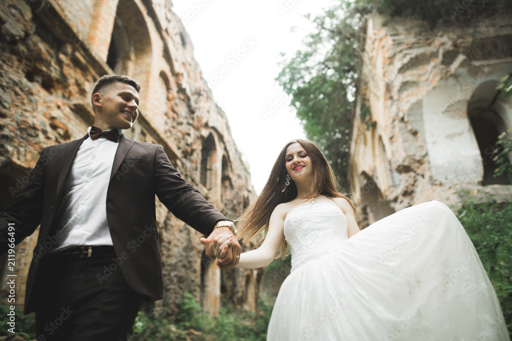Just married poses and kissing with an old fortress on the background Just married poses and kissing with an old fortress on the background
