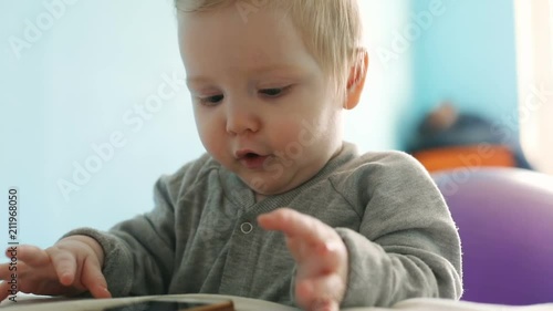 Cute caucasian 10 months 1 year old baby boy child standing on bright sunny background using smartphone mobile tapping touchscreen kid playing leisure children technology internet addiction concept photo