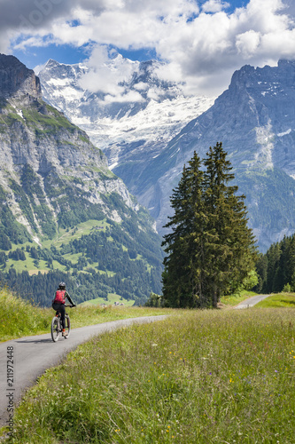 nice and ever young senior woman riding her e-mountainbike below the Eiger Northface near Grindelwald and Wengen, Jungfrauregion, Switzerland
