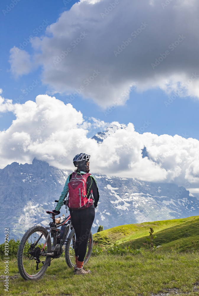 Fototapeta premium nice and ever young senior woman riding her e-mountainbike below the Eiger Northface near Grindelwald and Wengen, Jungfrauregion, Switzerland