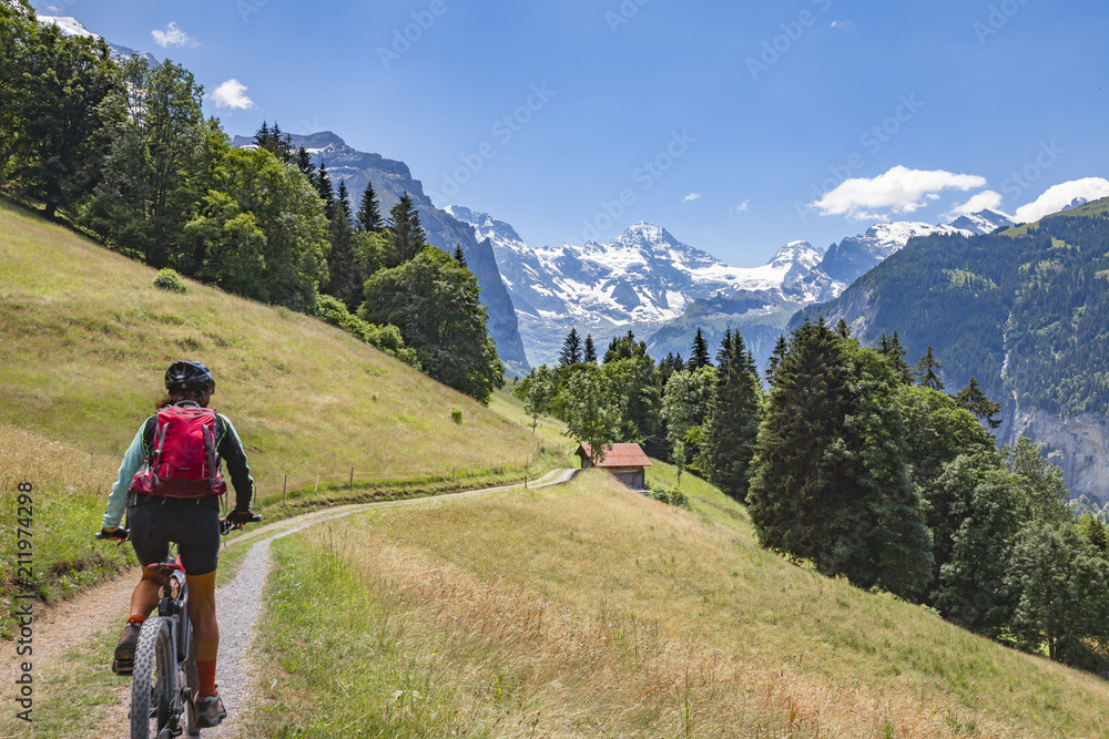 nice and ever young senior woman riding her e-mountainbike below the Eiger northface, Jungfrauregion, Switzerland