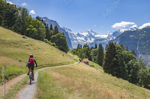 nice and ever young senior woman riding her e-mountainbike below the Eiger northface, Jungfrauregion, Switzerland