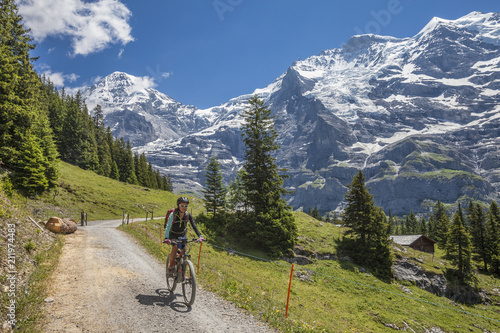 nice and ever young senior woman riding her e-mountainbike below the Eiger northface, Jungfrauregion, Switzerland