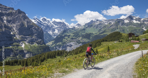 nice senior woman, riding her e-mountainbike on the Lauberhorn downhill from Kleine Scheidegg to Wengen and Lauterbrunnen,Jungfrauregion,Switzerland