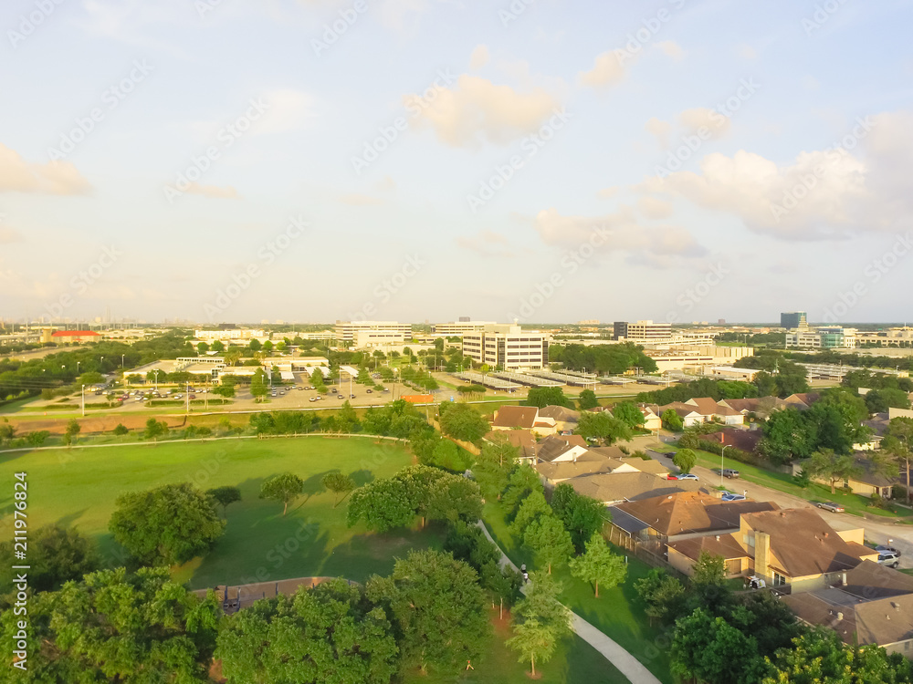 Aerial park near residential houses with business district building in background. Green urban recreation spot green tree, grassy lawn in Houston, Texas, US. Tightly packed homes neighborhood flyover